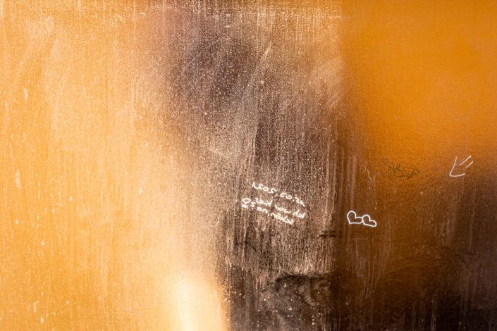 beschmierte Glasscheibe vor einer orangen Wand