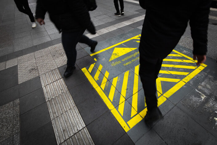 gelbe Beschriftung "Bitte weitergehen" am Boden im Kölner Hauptbahnhof