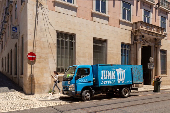 Streetfotografie in Lissabon; eine junge Frau geht an einem blauen Müllwagen vorüber