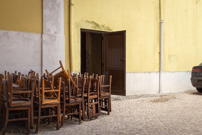 aufgehäufte Holzstühle im Hinterhof einer Kirche in Lissabon