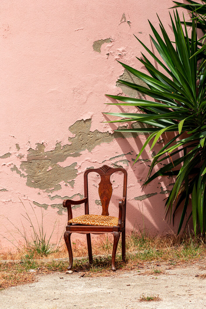 Ein alter Stuhl vor einer rosaroten Mauer