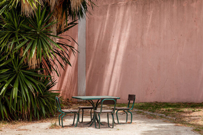 Ein Tisch mit Stühlen vor einer rosaroten Mauer