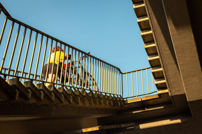 Eine Radfahrerin trägt ihr Fahrrad die Treppen zur Kölner Südbrücke hoch