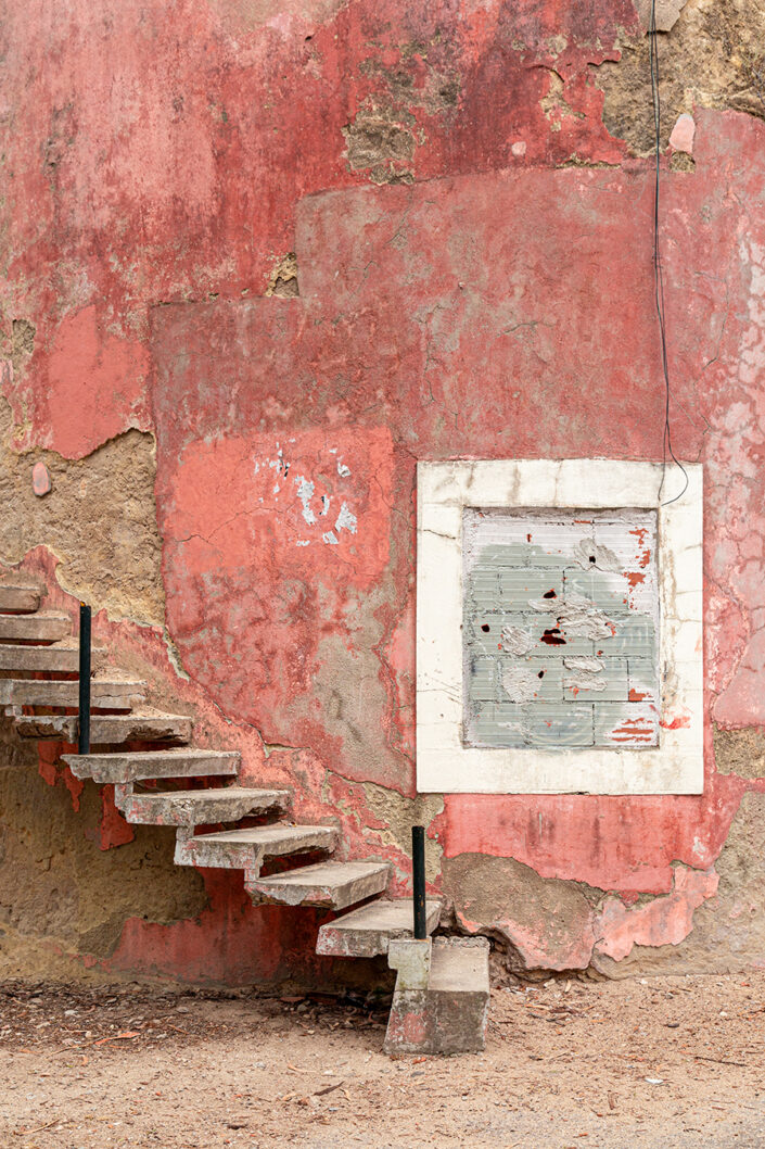 Eine alte Steintreppe vor einer rosaroten Mauer
