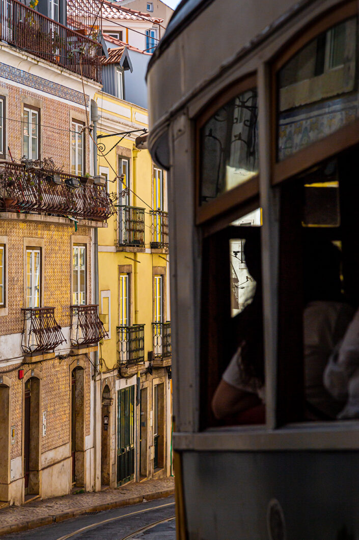 Eine Tram, die an alten Häuserfassaden in Lissabon vorbei fährt