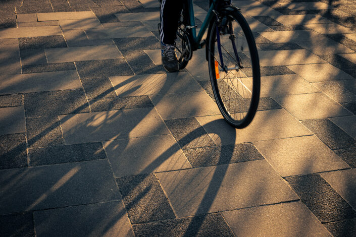 Ein Fahrrad, das in der Nachmittagssonnen Schatten auf ein Pflaster wirft.