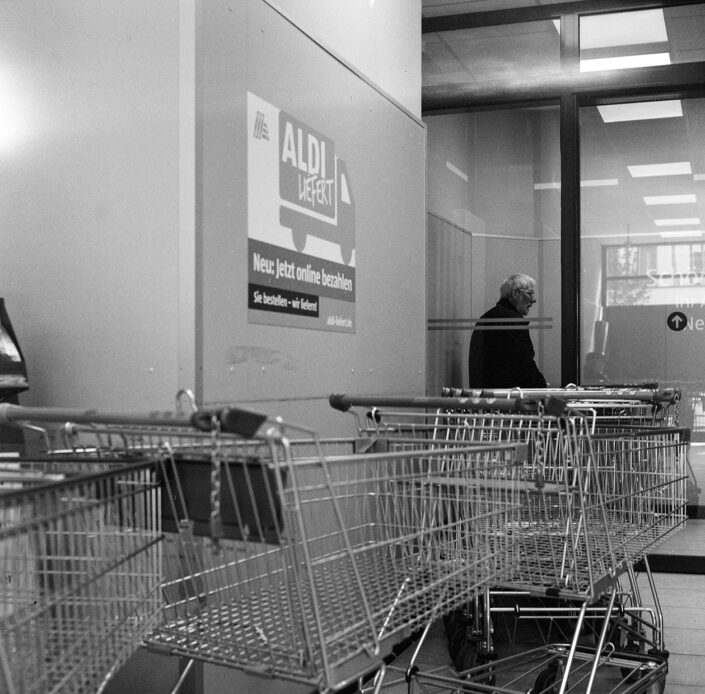 Abgestellte Einkaufswagen im Eingangsbereich einer Aldi Filiale, analog in Schwarz-Weiß fotografiert